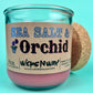 Recycled glass candle front view, pink wax, blue-and-black printed label, cork behind