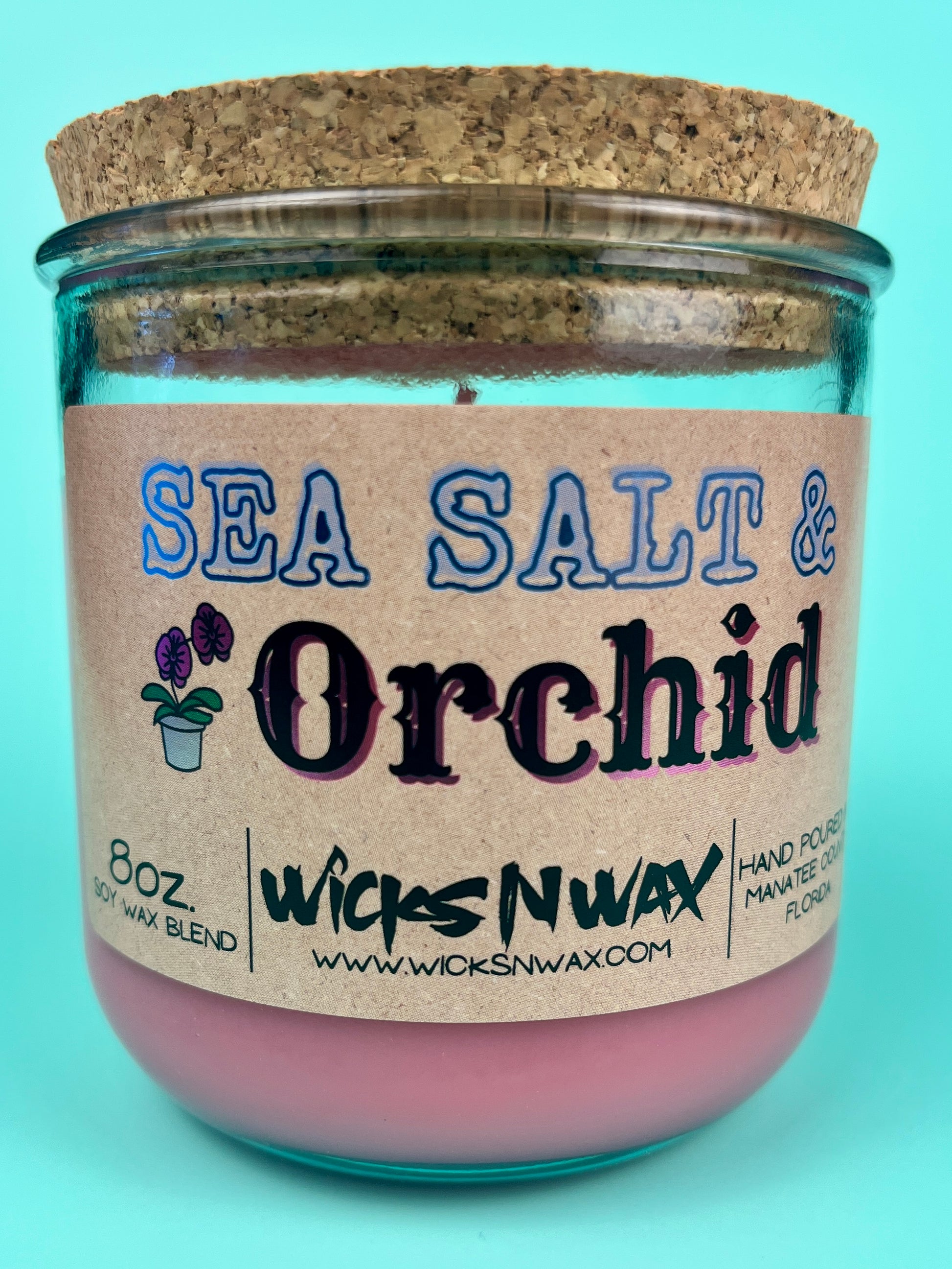 Recycled glass candle close-up, pink wax with cork lid, blue-and-black label