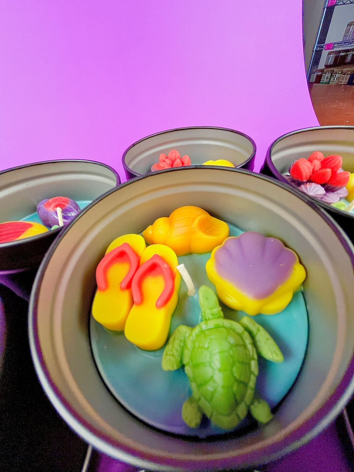 Large metal candle tin featuring yellow footprints, purple shell, and green turtle wax