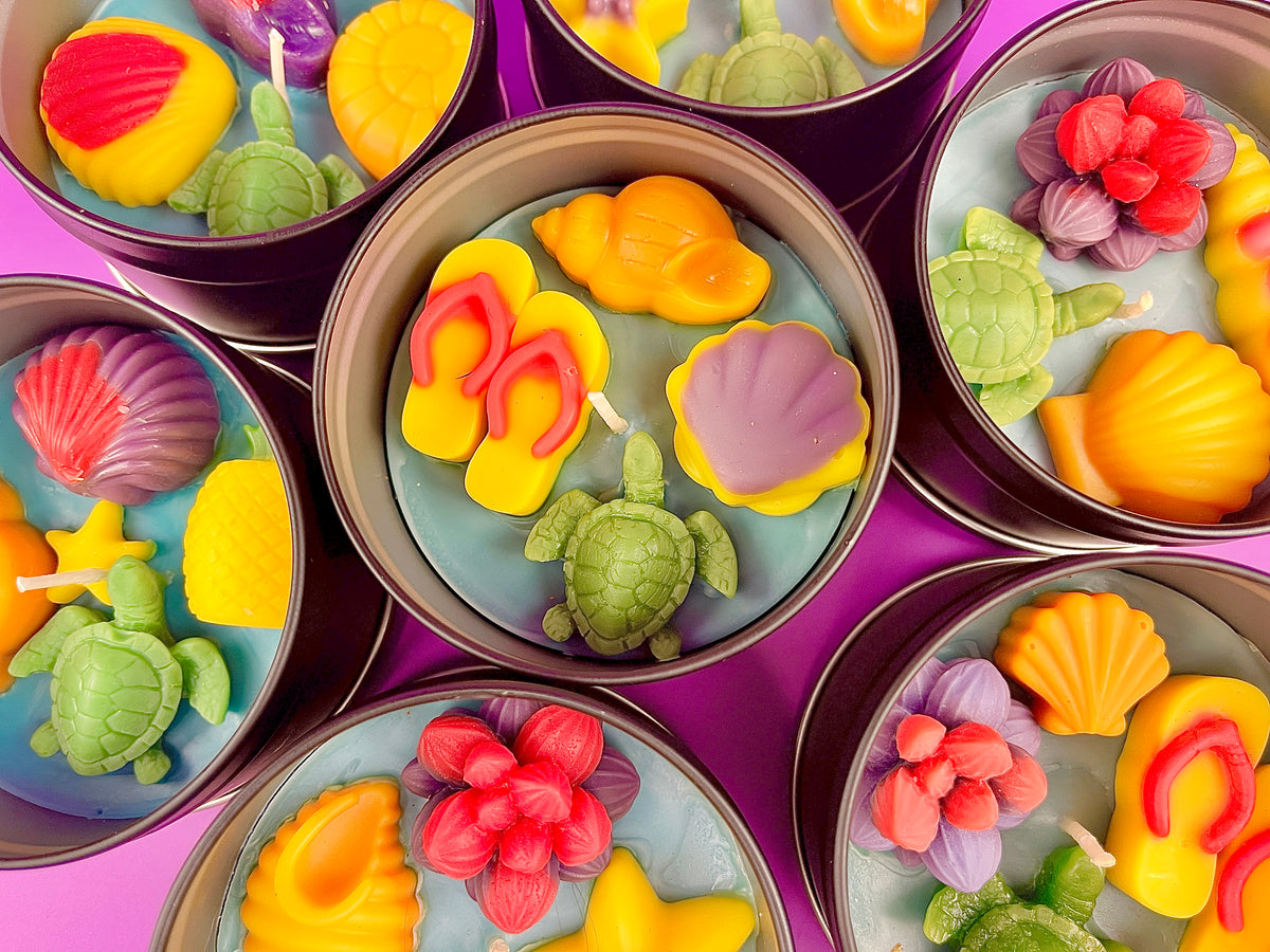 Assorted sea-themed wax candle tins with purple, orange, green, and red flower pieces