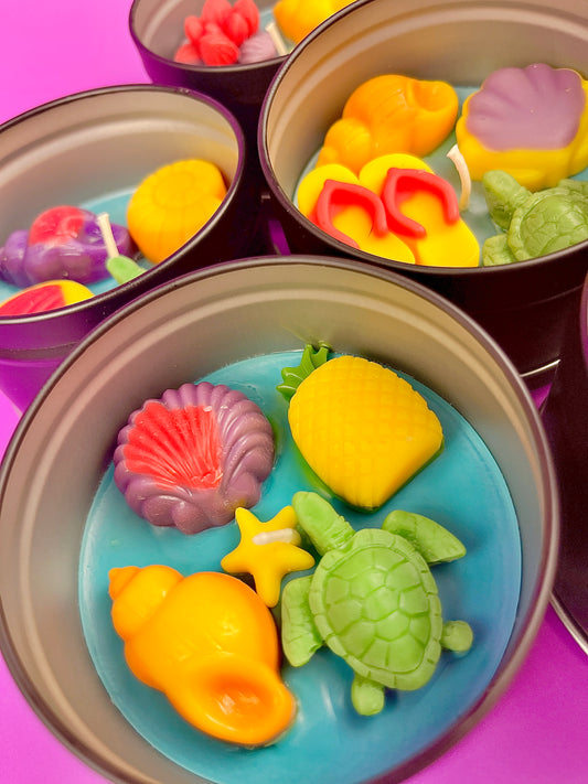 Sea-themed wax candles in metal tins with yellow, purple, green, and orange pieces