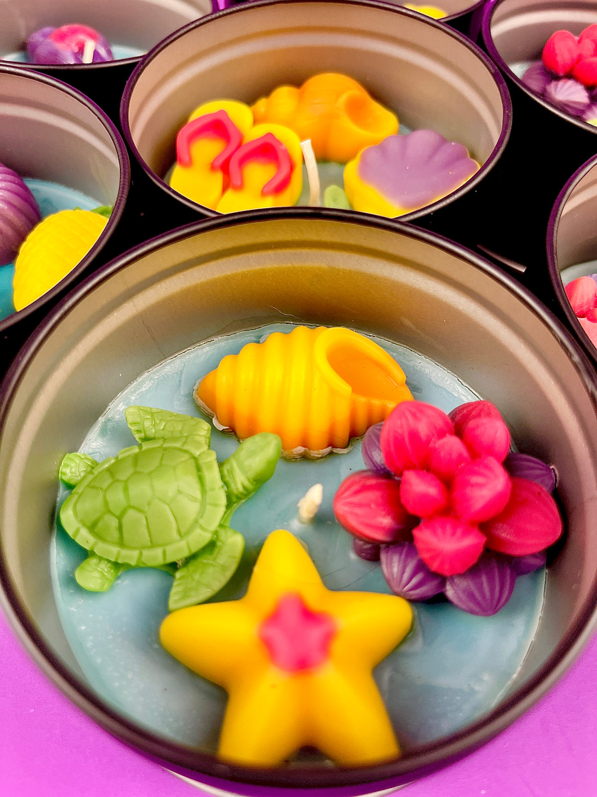Large metal candle tin with orange shell, pink flower, yellow star, and green turtle wax