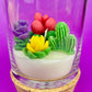 WicksNWax cactus art candle in clear glass with colorful cactus wax flowers and white wax
