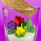Small cactus art candle with cork lid; clear glass with colorful cactus flower wax