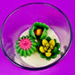 Small cactus art candle in clear glass with green cactus and pink/yellow wax blooms