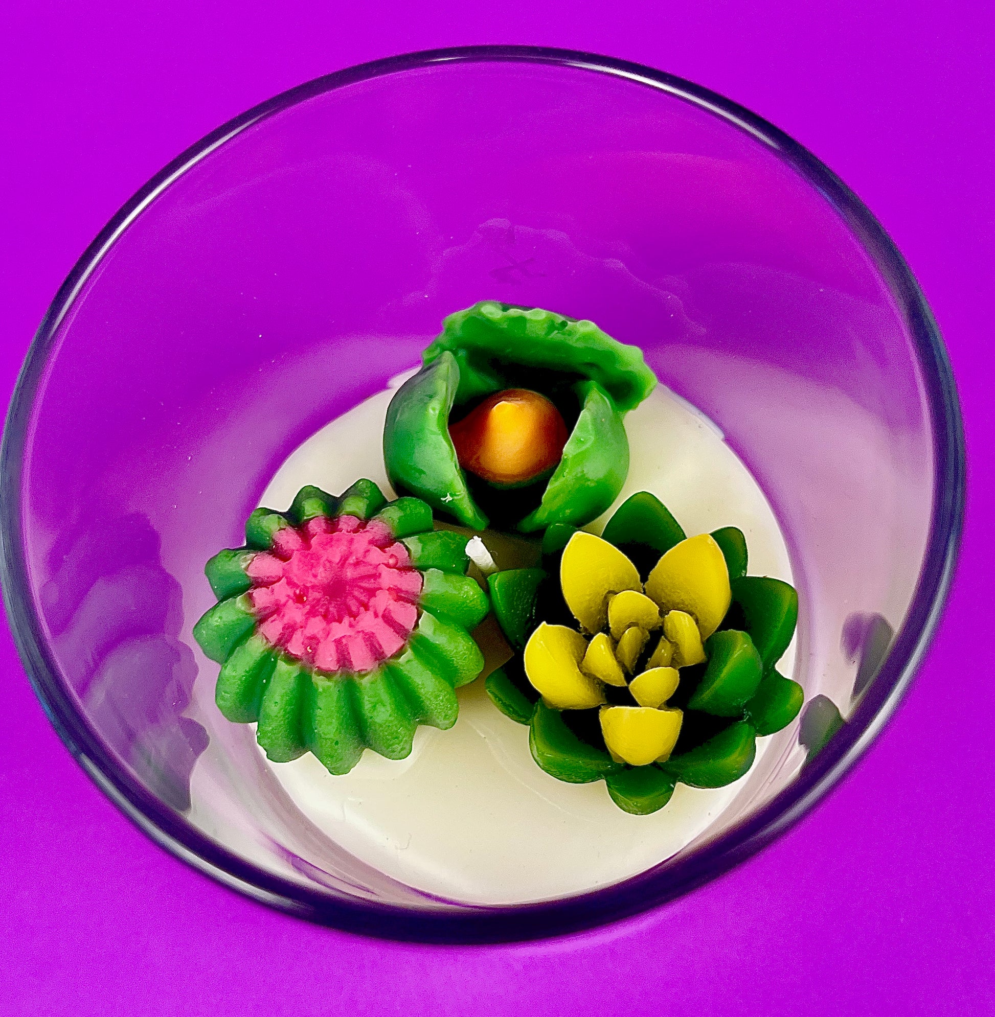 Small cactus art candle in clear glass with green cactus and pink/yellow wax blooms