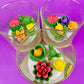 Small cactus art candle in glass jar with green, yellow and pink wax flowers