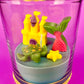 Small candle in glass with cork base, featuring castle and sea-creature wax