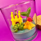 Small candle in glass container with pineapple, fish, and star-shaped wax pieces