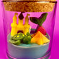 Small candle in glass container with castle, pineapple, and star-shaped wax pieces