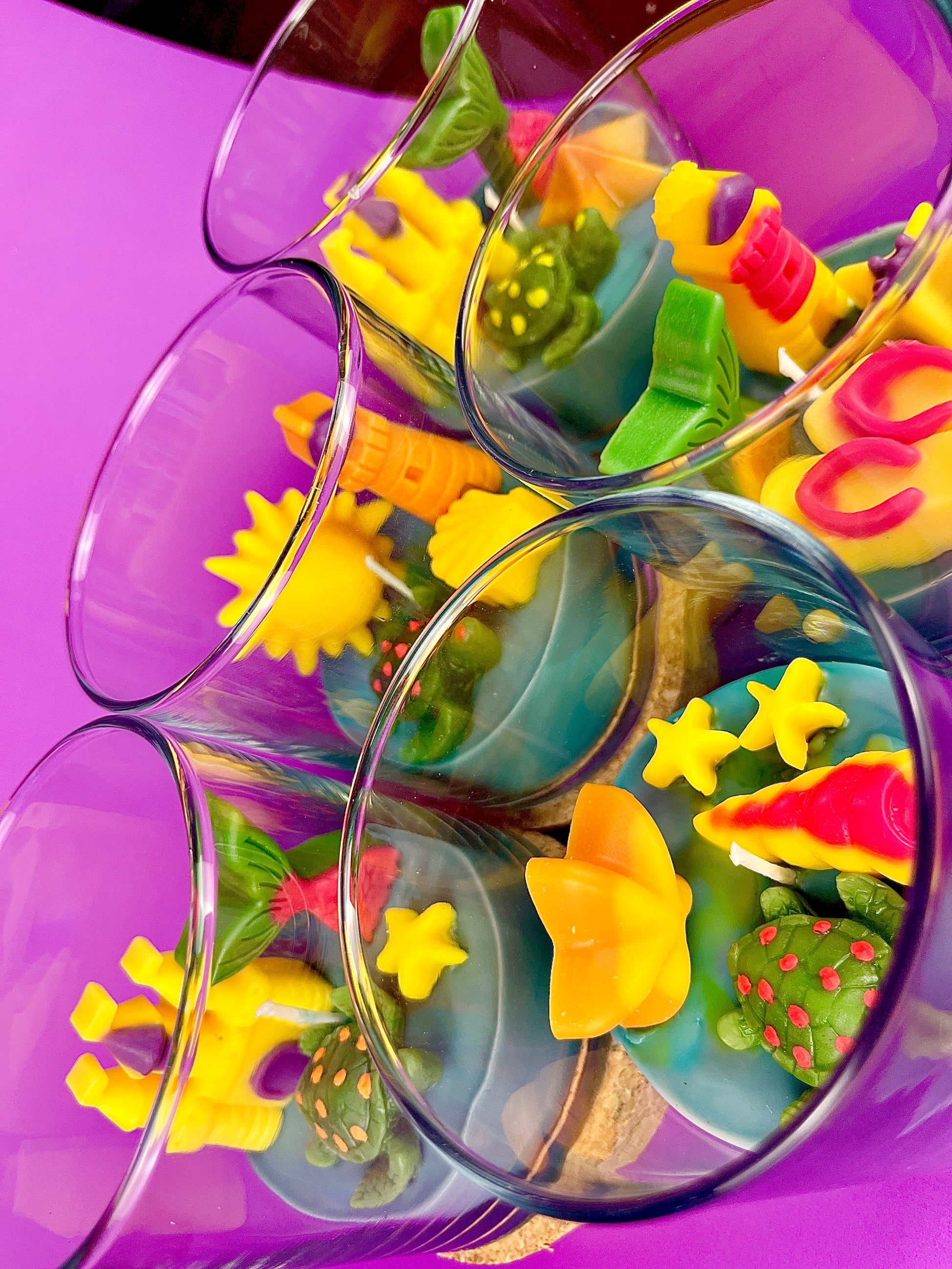 Small scented candle set in clear glass jars with assorted bright sea-shaped wax pieces