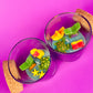 Small scented candle in clear glass jar with cork lid and assorted sea-shaped wax pieces