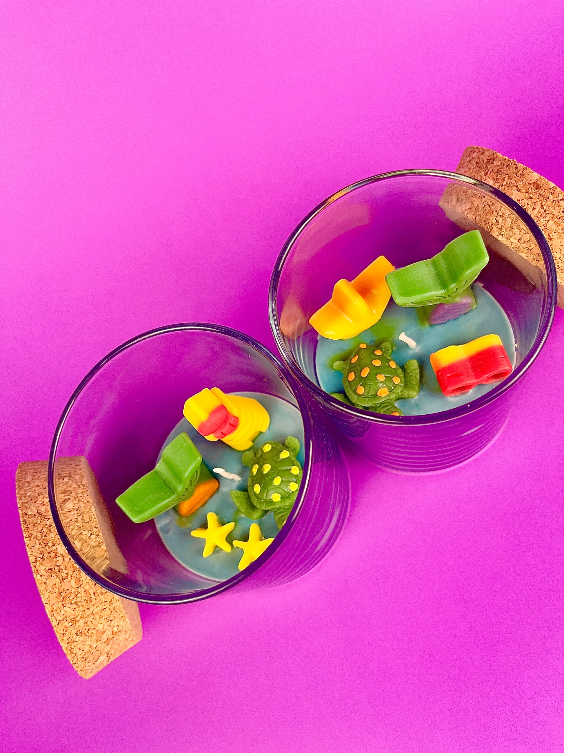 Small scented candle in clear glass jar with cork lid and assorted sea-shaped wax pieces