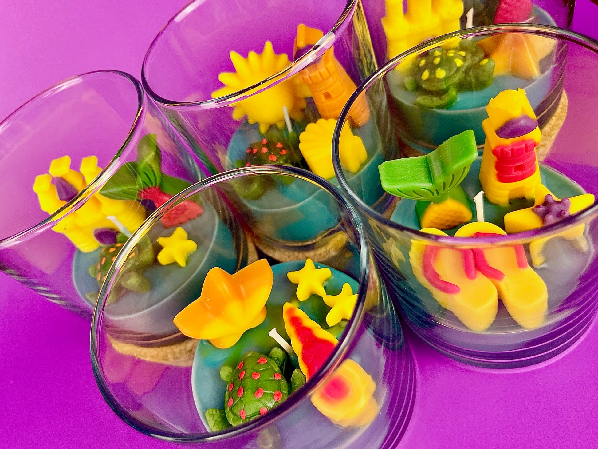 Small candles in glass with colorful shell and star-shaped wax pieces inside