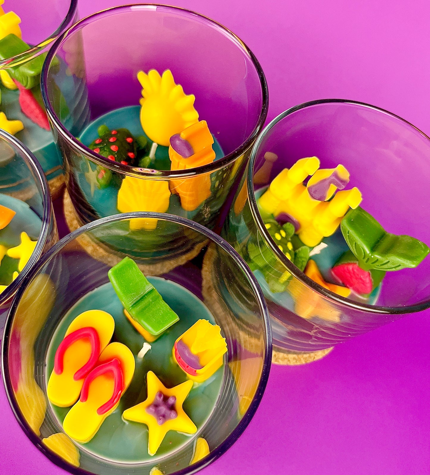 Small candle in glass container with assorted star and shell-shaped wax pieces