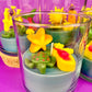 Small candle in glass with colorful star and seashell wax pieces