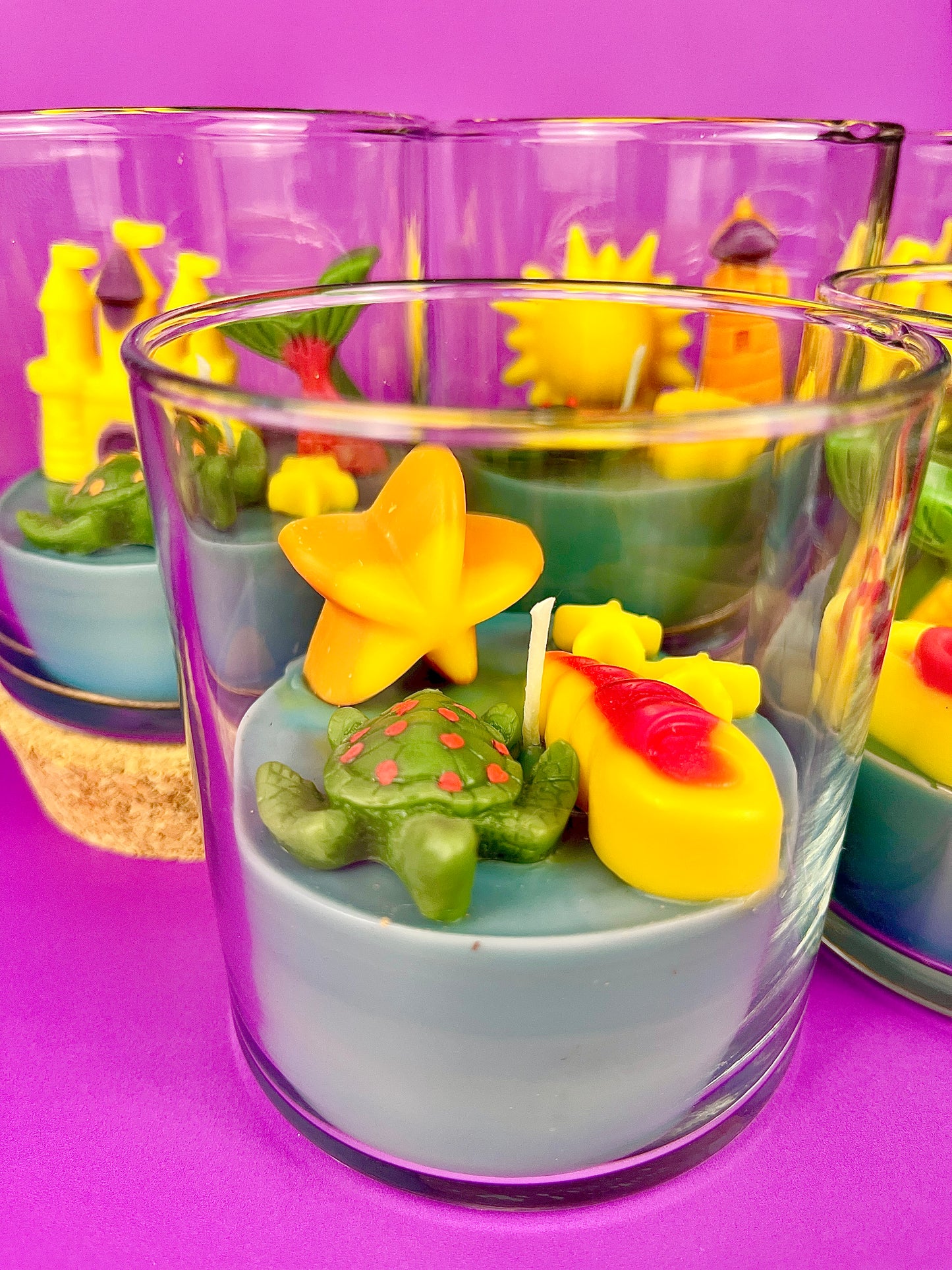 Small candle in glass with colorful star and seashell wax pieces