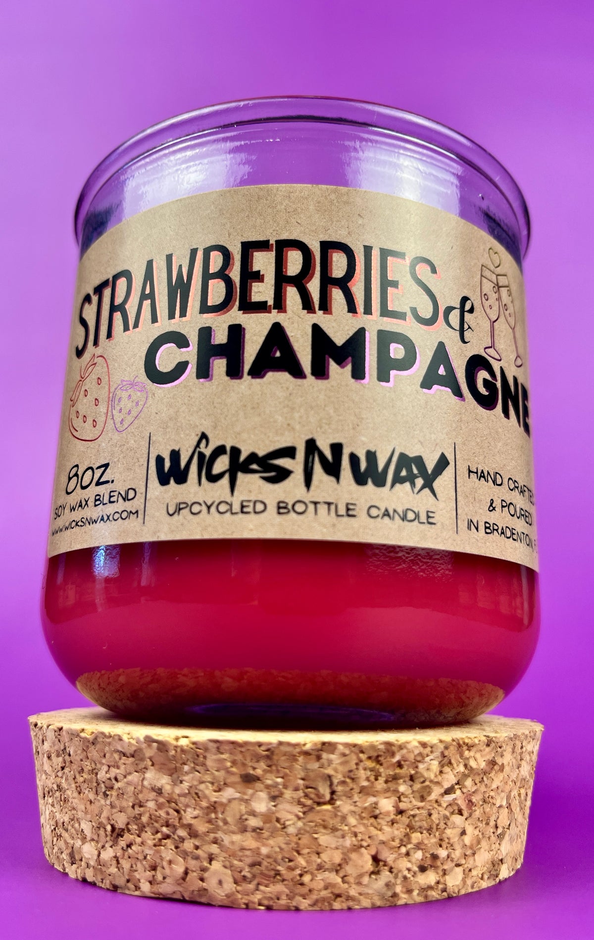 Recycled glass candle with cork base, red wax, 'Strawberries & Champagne' label.