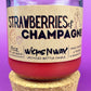 Recycled glass candle with cork base, red wax, 'Strawberries & Champagne' label view.