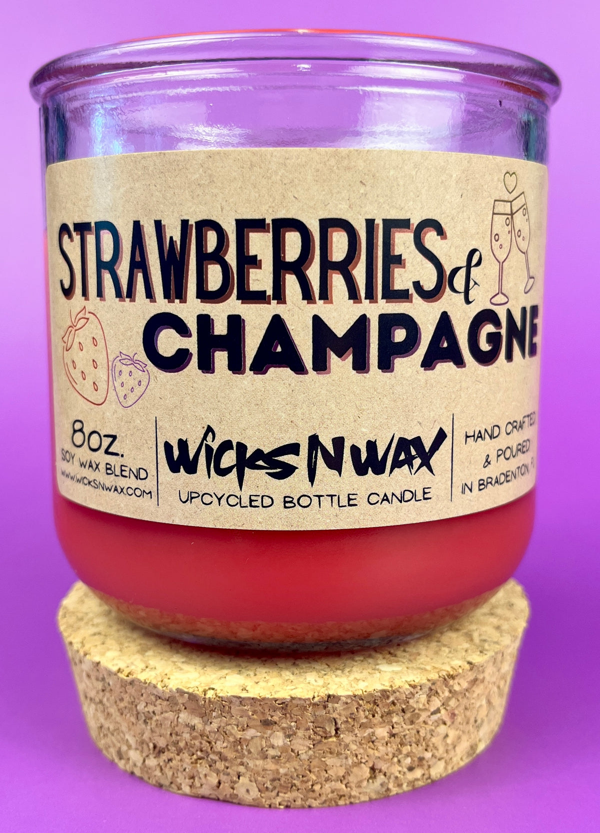 Recycled glass candle with cork base, red wax, 'Strawberries & Champagne' label view.