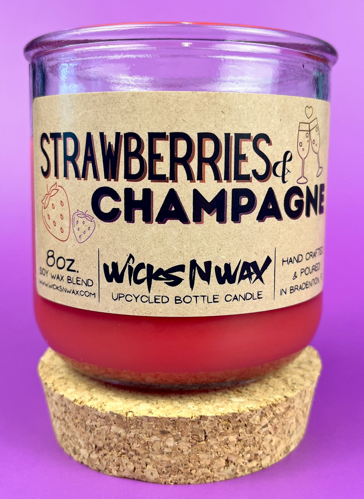 Recycled glass candle with cork base, red wax, 'Strawberries & Champagne' label.