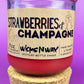 Recycled glass candle with cork base, red wax, 'Strawberries & Champagne' text.