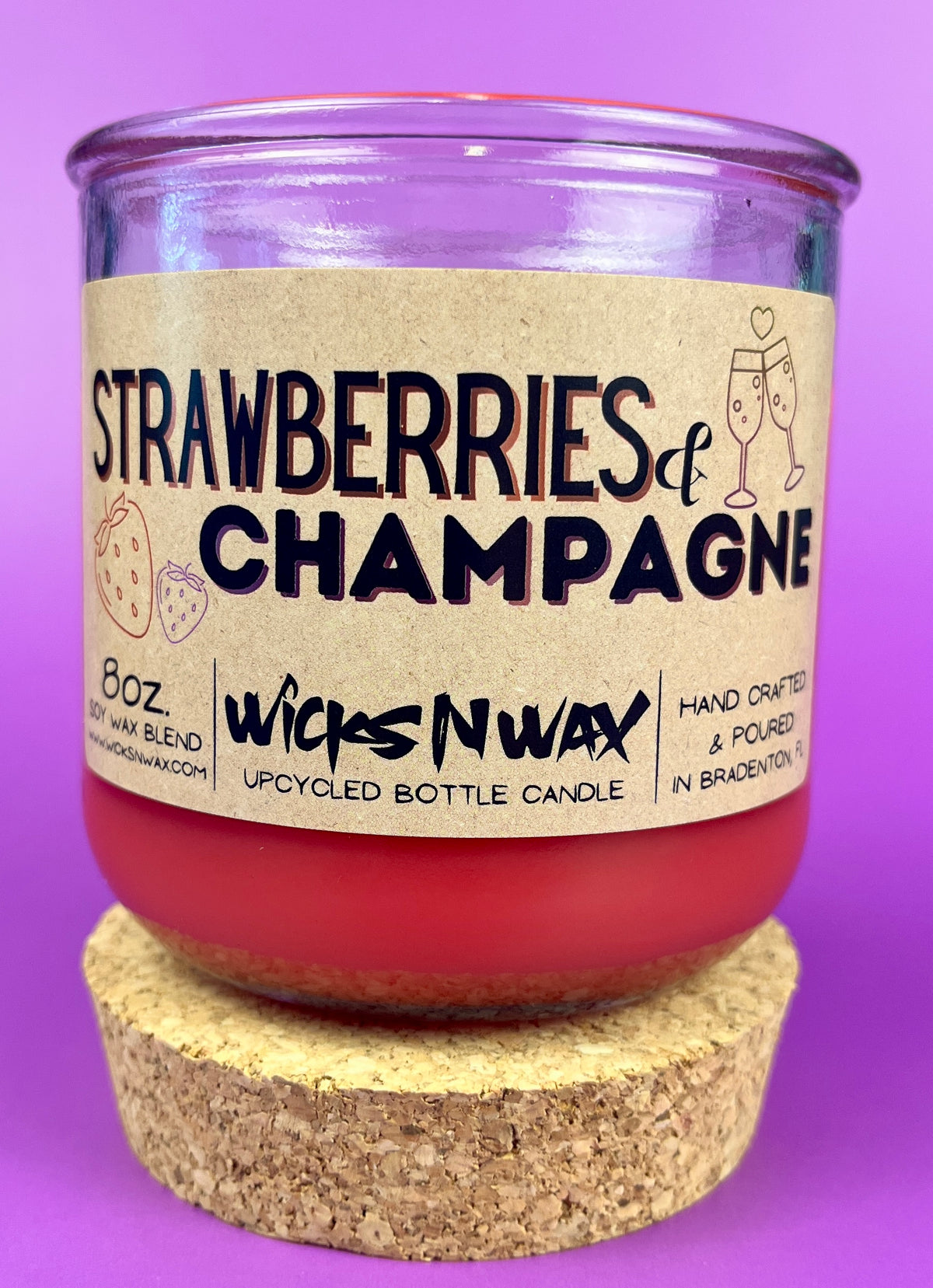 Recycled glass candle with cork base, red wax, 'Strawberries & Champagne' text.