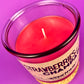 Red wax candle in clear glass jar, small white wick visible.