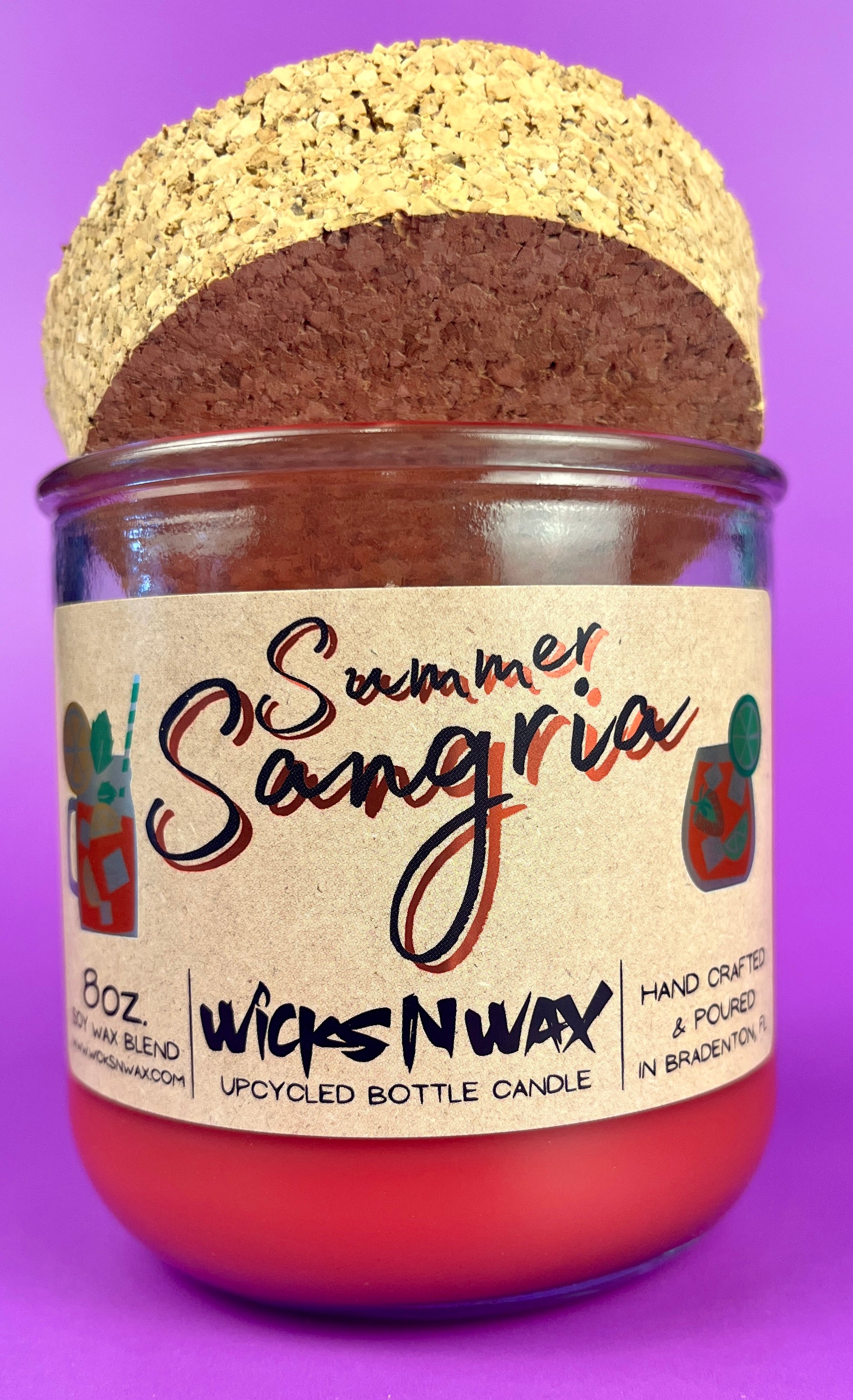 Recycled glass bottle candle with red wax, cork lid, and printed label on jar