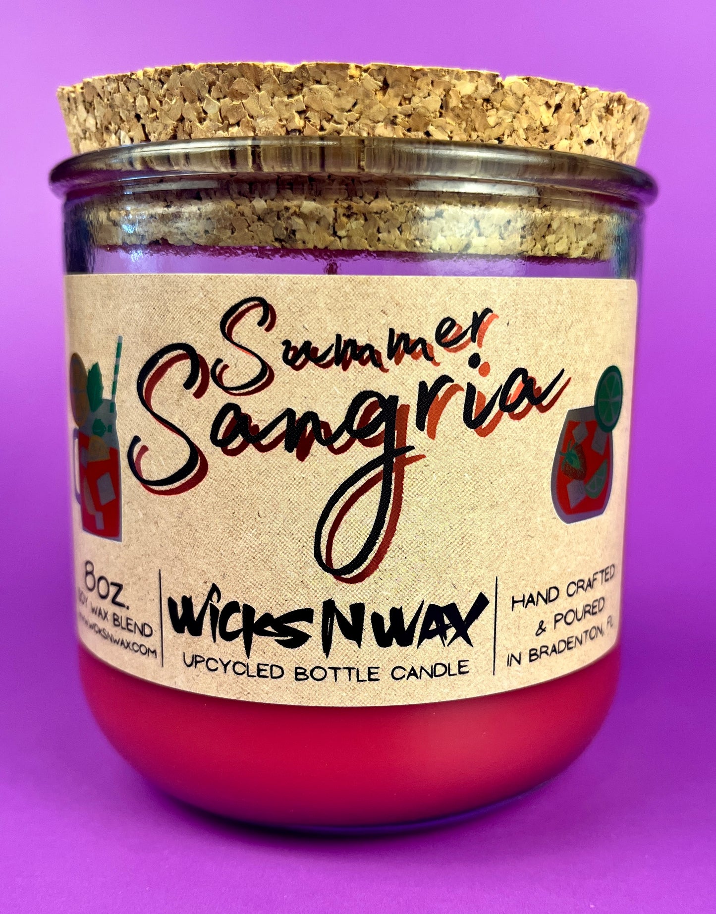 Recycled glass bottle candle with red wax, cork lid, and printed label on jar