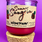 Recycled glass bottle candle with red wax, cork base, and printed label on jar