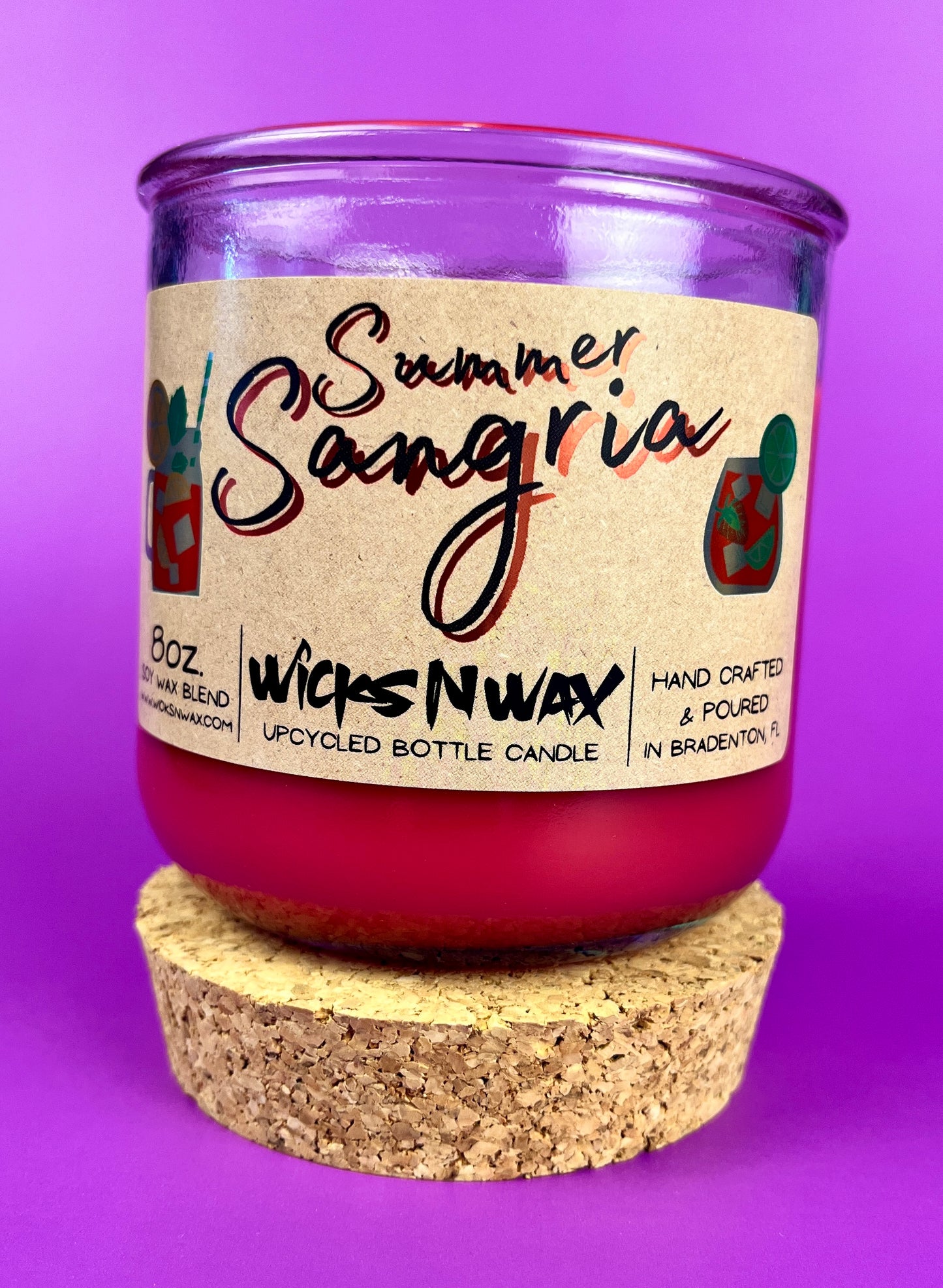 Recycled glass bottle candle with red wax, cork base, and printed label on jar