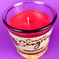 Recycled glass bottle candle with red wax and visible wick through clear rim