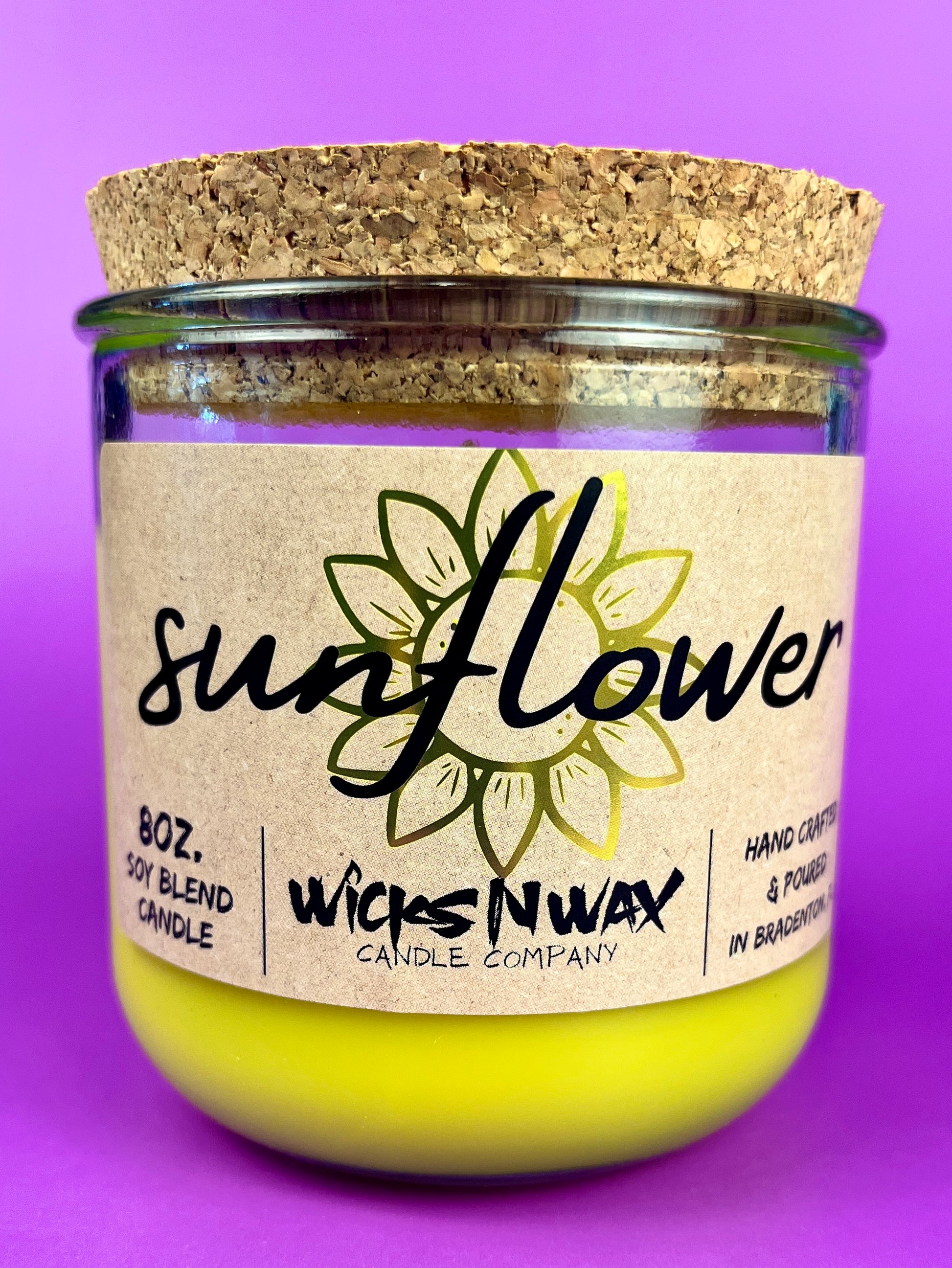 Recycled glass candle with sunflower label and yellow wax in clear jar