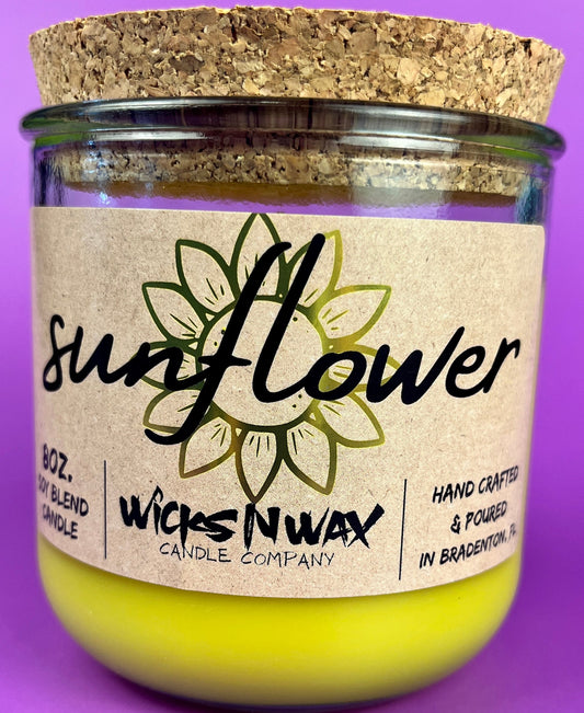 Recycled glass candle with sunflower label, yellow jar, and cork lid, WicksNWax