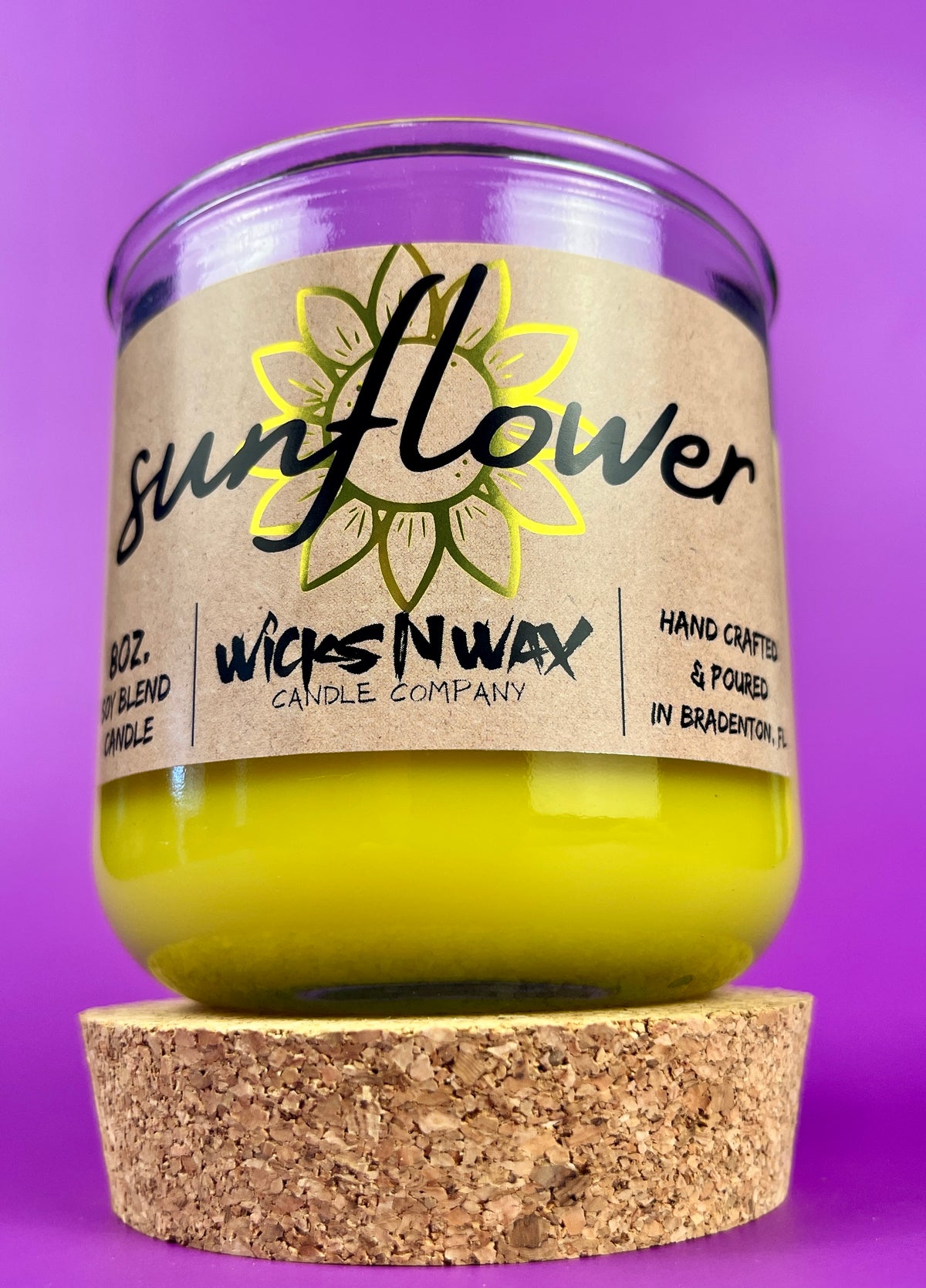 Recycled glass candle with sunflower label and yellow wax, cork base visible