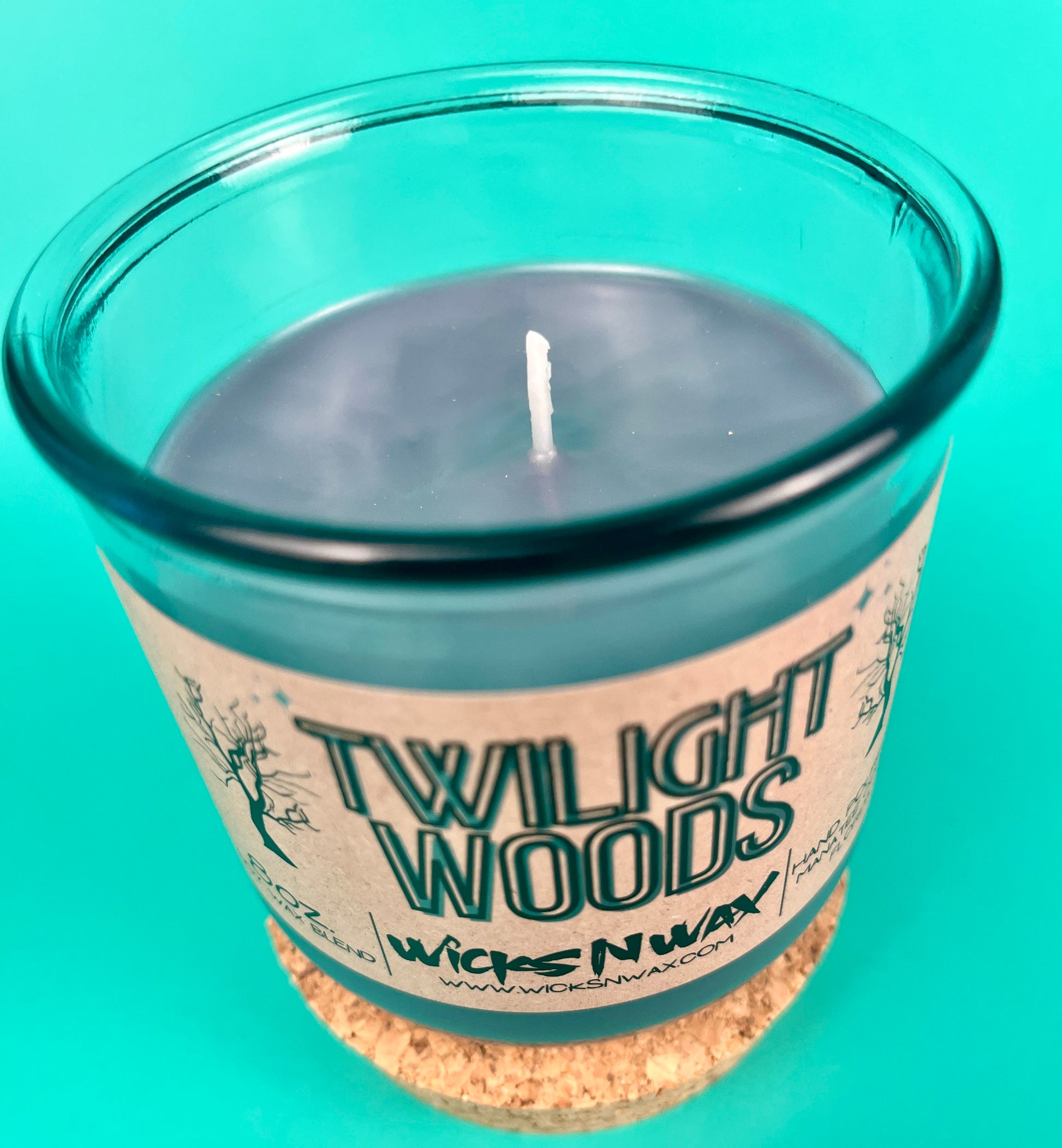 Blue glass candle jar with wick visible and Twilight Woods label on front