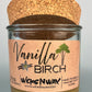 Vanilla Birch recycled glass candle with tan wax, clear glass jar, and cork lid behind label