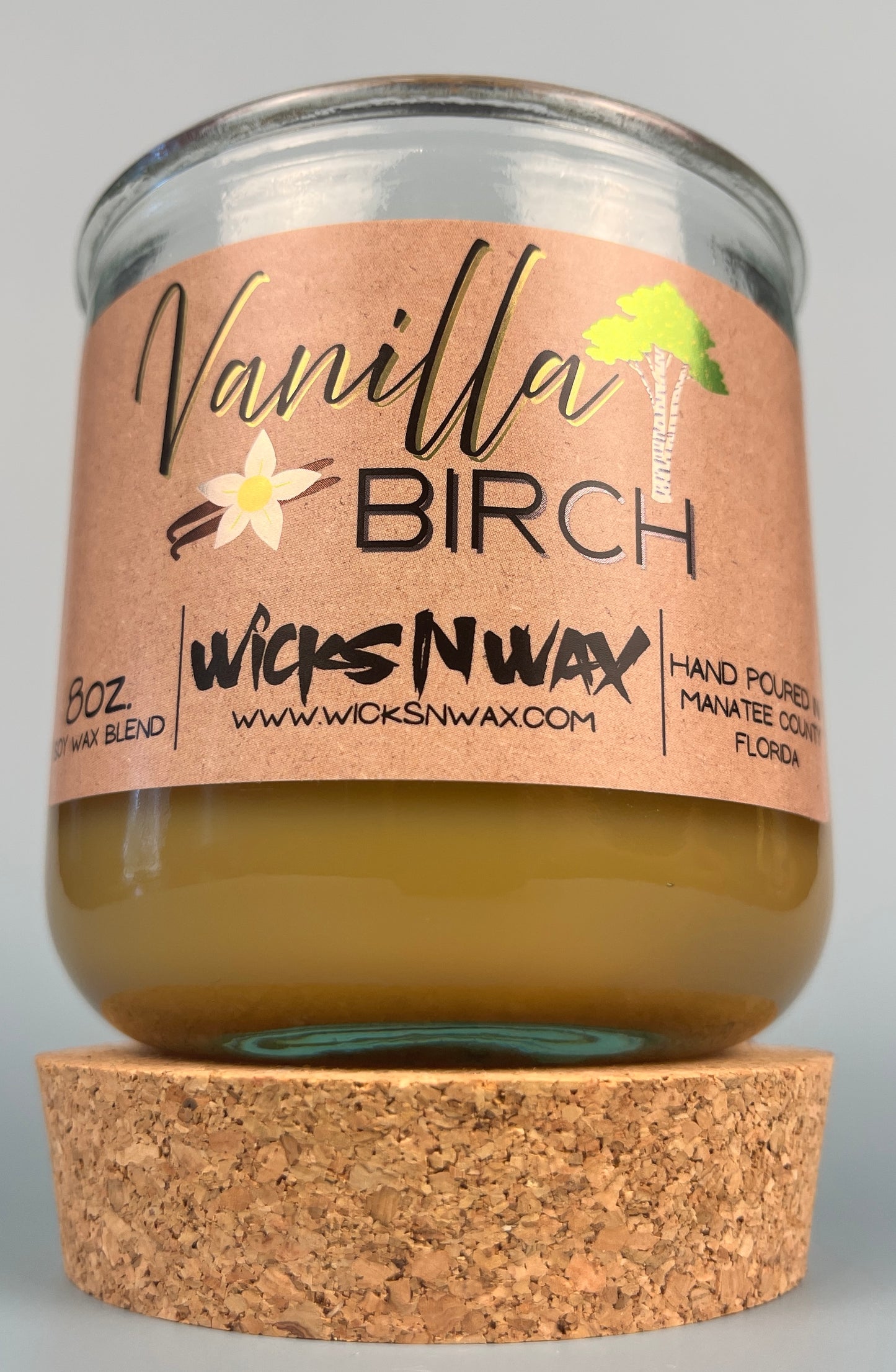 Vanilla Birch recycled glass candle with tan wax, clear jar, kraft label, and cork base
