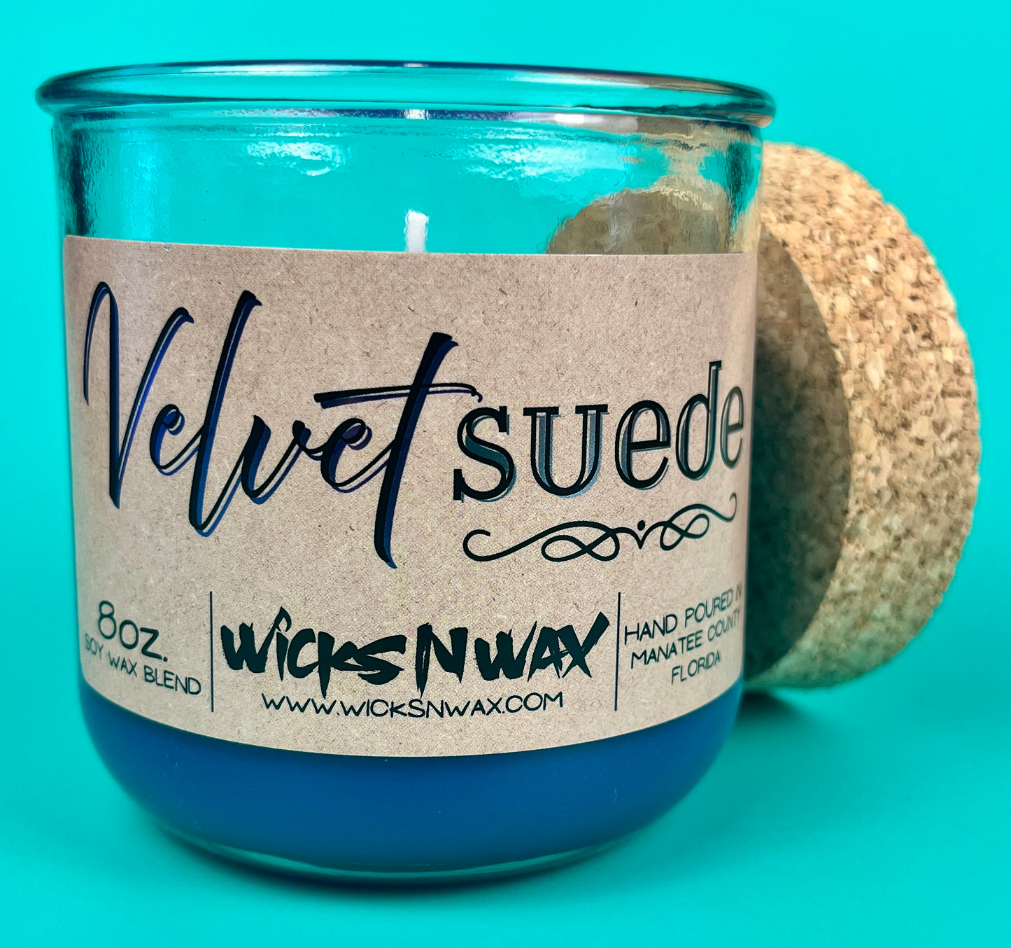 Teal glass candle jar with kraft label, cork lid, and centered wick