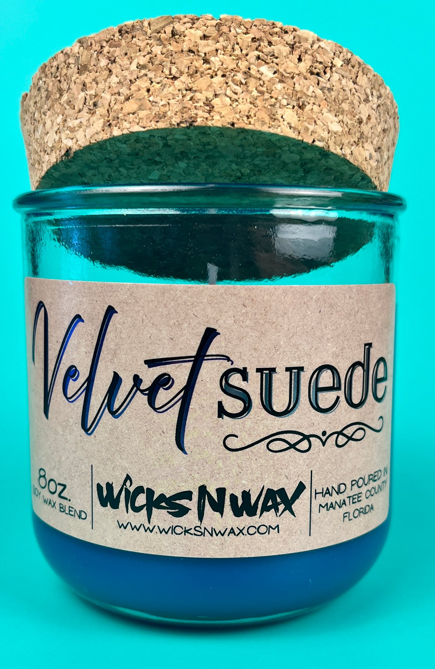 Teal glass candle jar with kraft label, cork lid, and visible wick