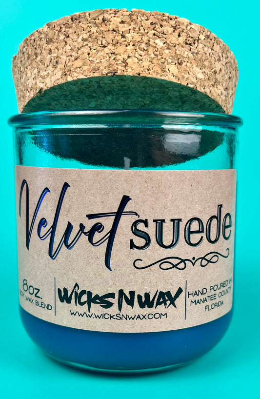 Teal glass candle jar with kraft label, cork lid, and visible wick
