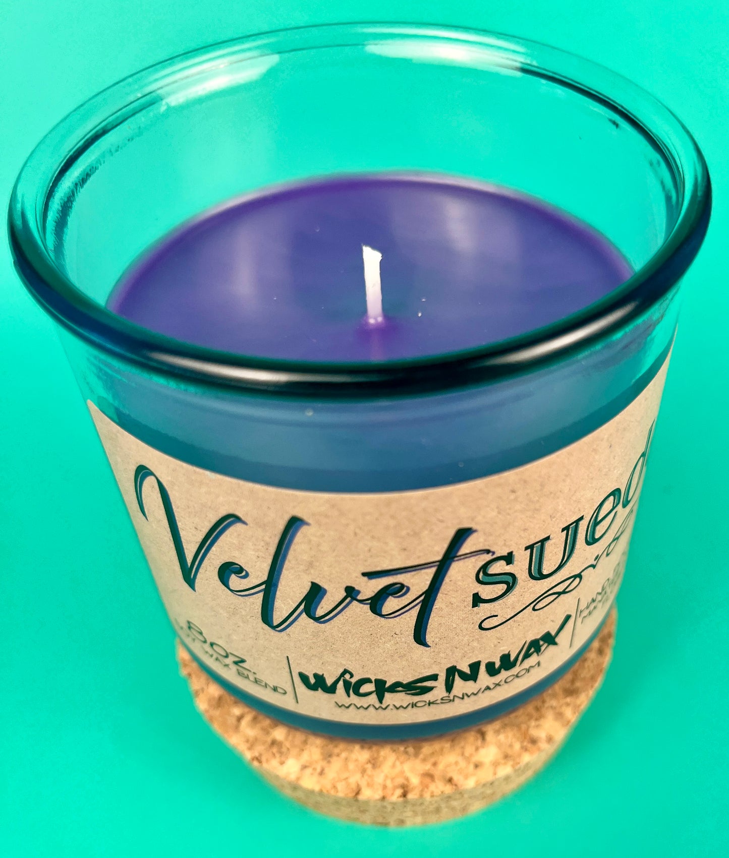Teal glass candle jar with kraft label and centered wick
