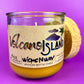 Recycled glass candle jar with Volcano Island label and yellow wax, cork base partially visible