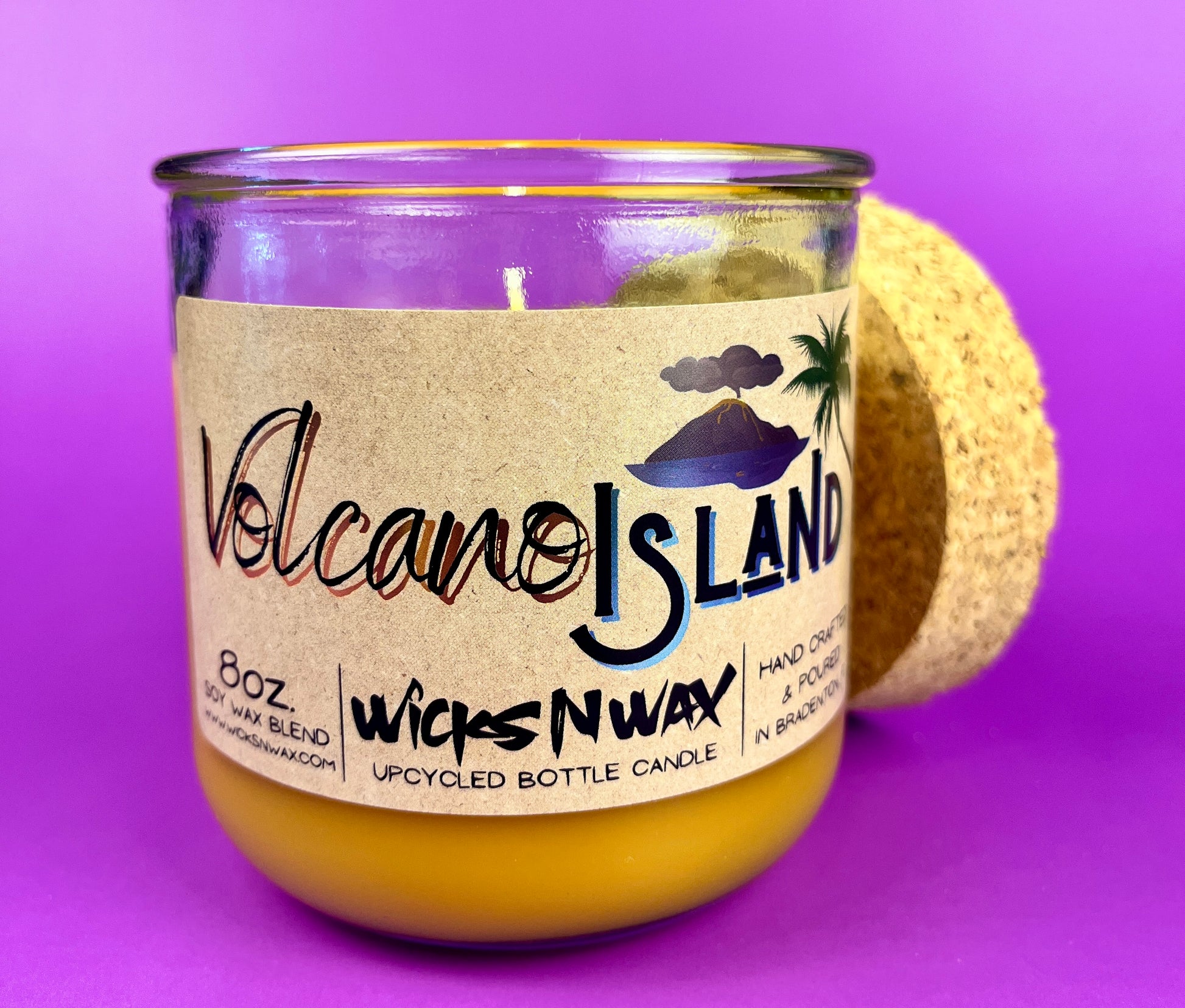 Recycled glass candle jar with Volcano Island label and yellow wax, cork base partially visible