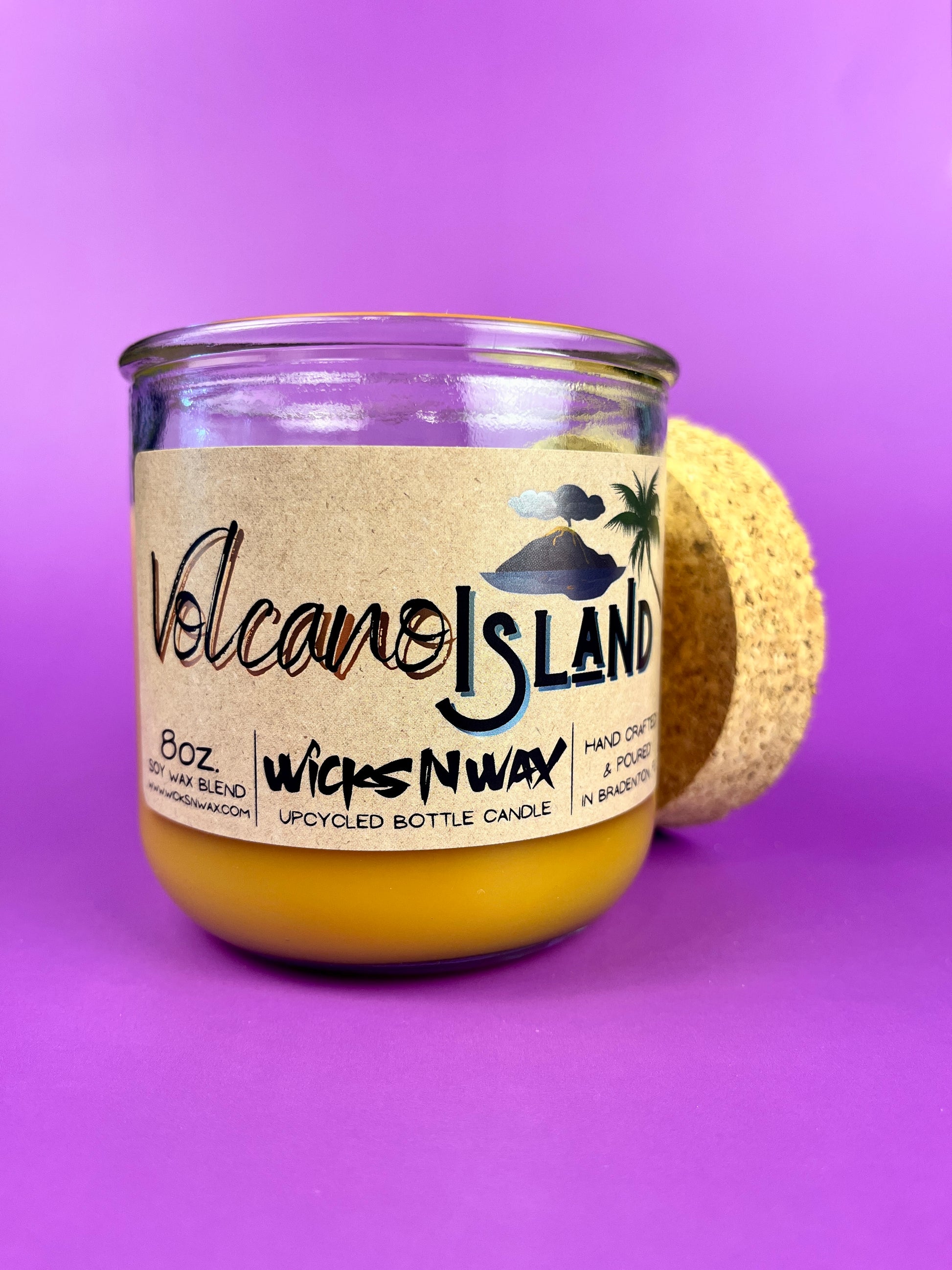 Recycled glass candle jar with Volcano Island label, yellow wax, cork base in side view