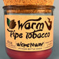 Glass bottle candle with red wax, leaf-and-smoke graphic label, cork top exposed