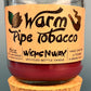Glass bottle candle with red wax, leaf-and-smoke graphic label, on cork base