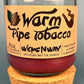 Glass bottle candle with red wax, leaf-and-smoke graphic label, on cork base