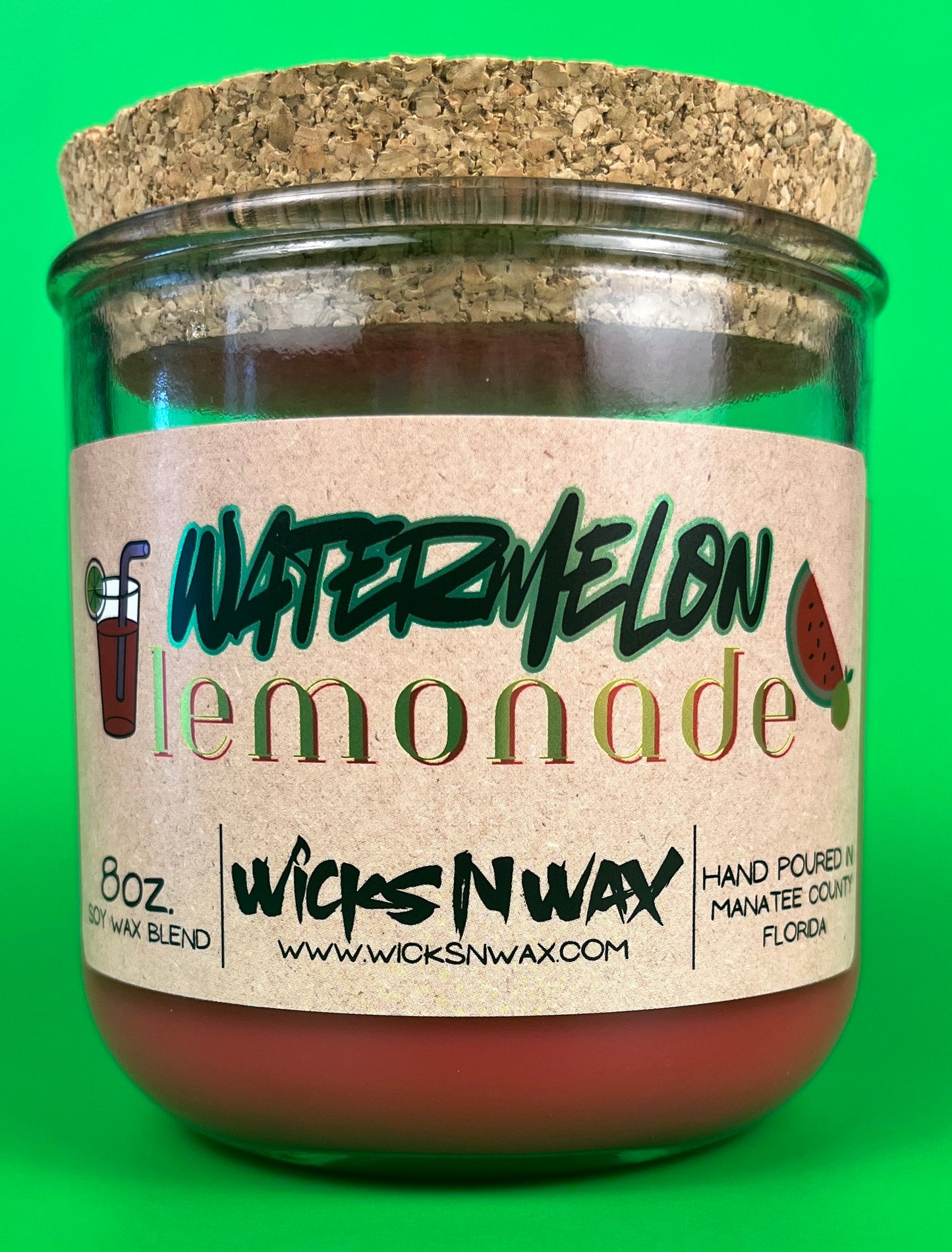 Glass candle jar with red wax and dark label text for watermelon lemonade, cork base